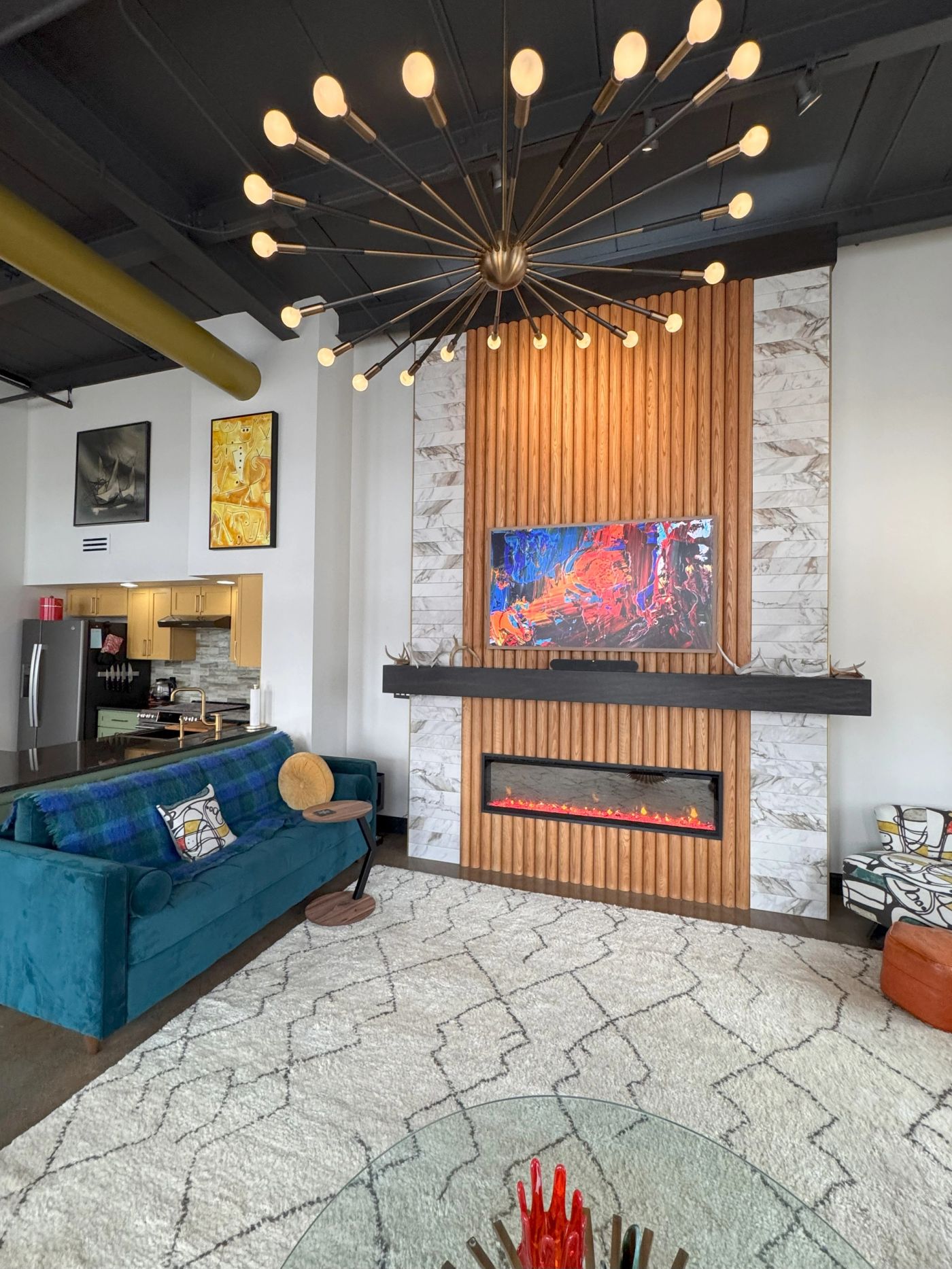 Downtown loft by Daniel Home with a fluted timber fireplace wall and a sputnik chandelier